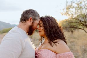 An intimate moment between a couple in a desert setting with soft lighting.