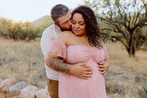 A tender embrace captured in a pink dress against a desert landscape.