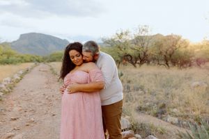 A loving couple shares a moment on a desert path with mountains visible in the distance.
