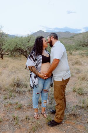 A couple shares an intimate moment on a desert trail wearing casual attire.