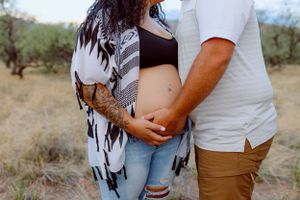 A close-up maternity photo showing a baby bump with a patterned cardigan.