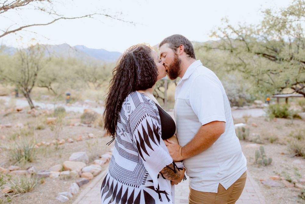 Couple sharing romantic moments in a desert setting with mountains and brush.