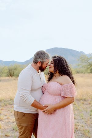 Loving couple shares tender moment during desert maternity session.