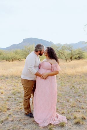 A romantic couple shares a tender moment in a desert landscape with mountains in the background.