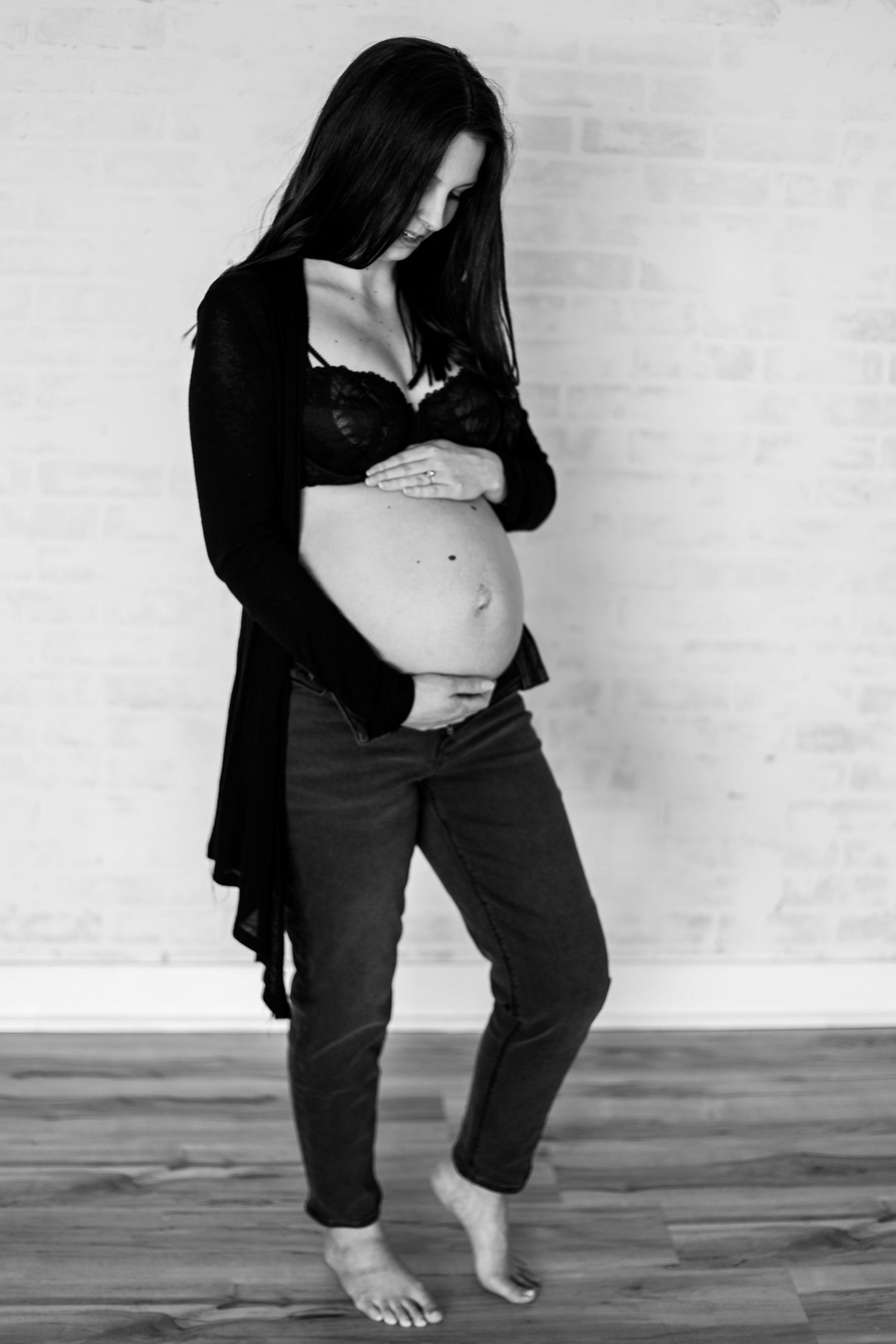Black and white maternity photo showing pregnant belly with black cardigan.