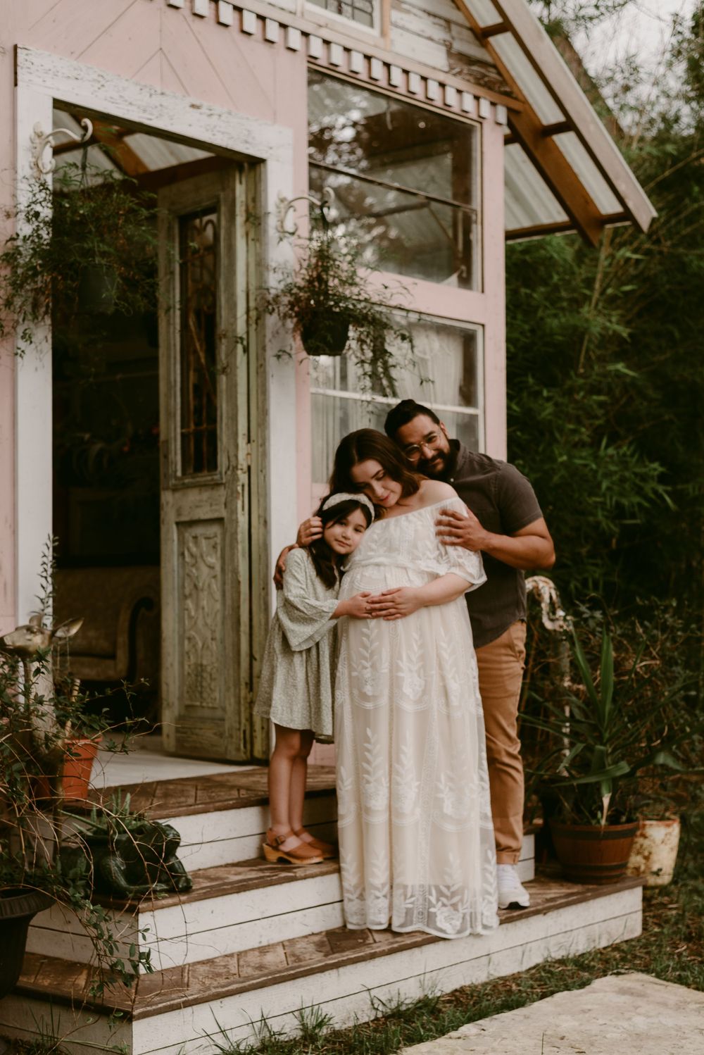 A loving family shares an embrace during their outdoor maternity photo session.