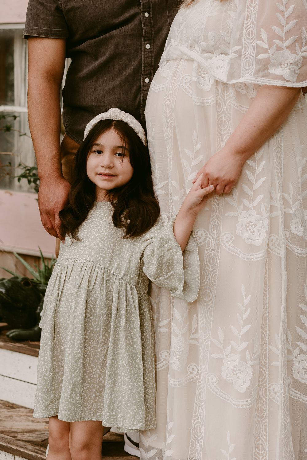 A sweet moment captured between a family as they stand together on wooden porch steps.