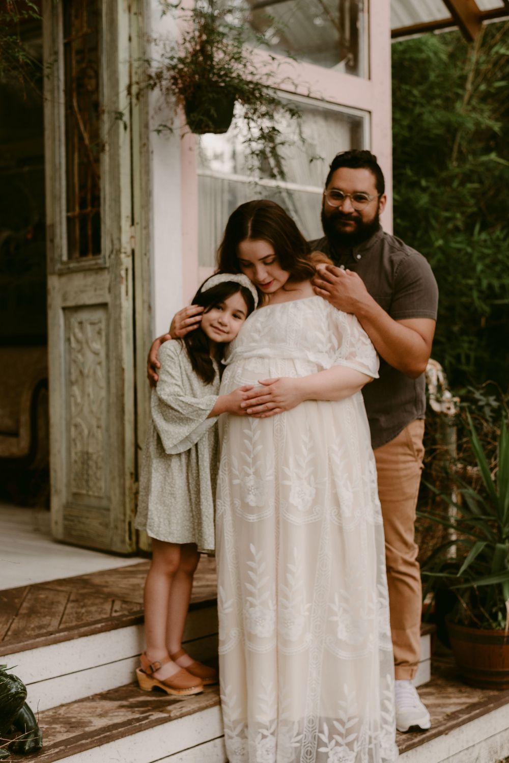 An emotional family moment captured during a maternity photoshoot on a rustic porch.