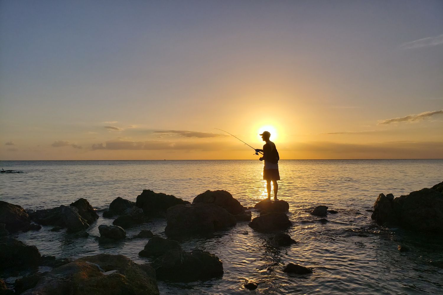 sunset rocks candid fisherman