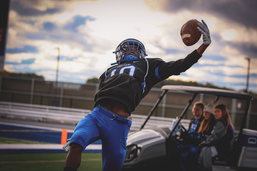 Football player leaping to make dramatic one-handed catch during game.