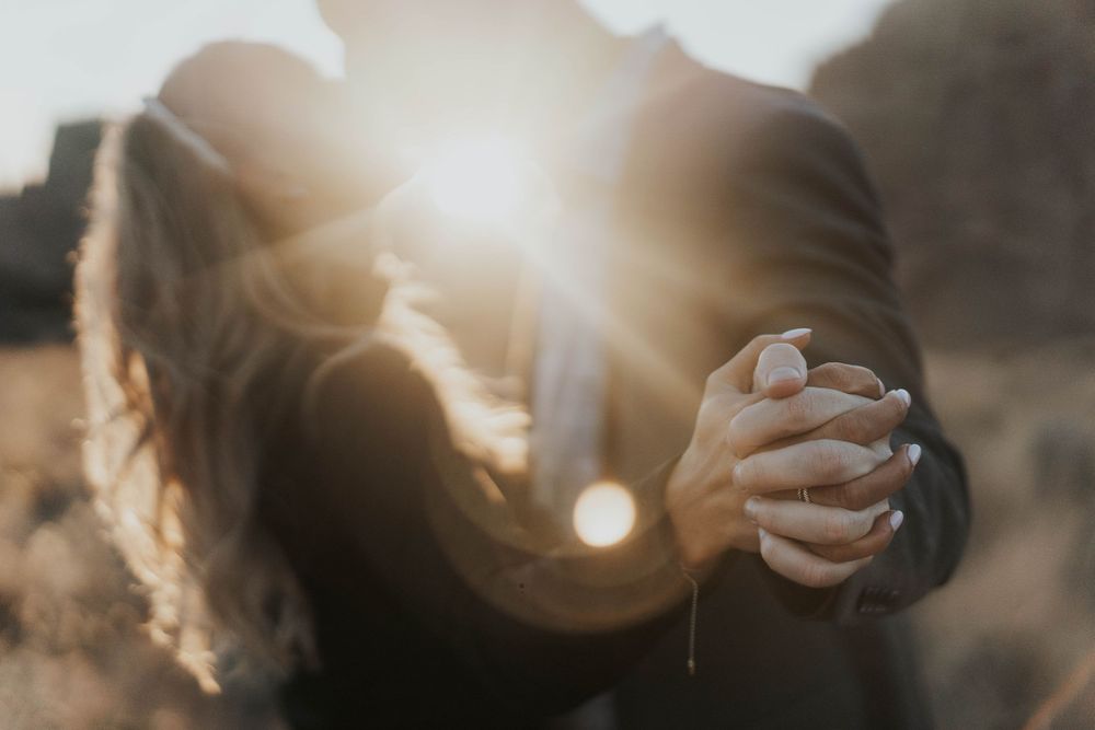 couple holding hands and kissing while the sun shines between them