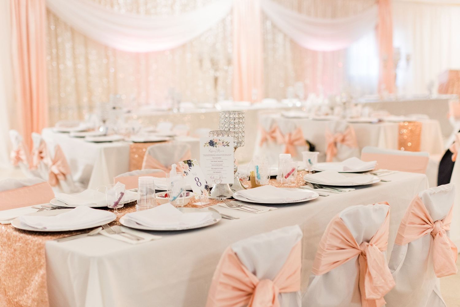 Elegant wedding reception table settings with pink bows and white linens.