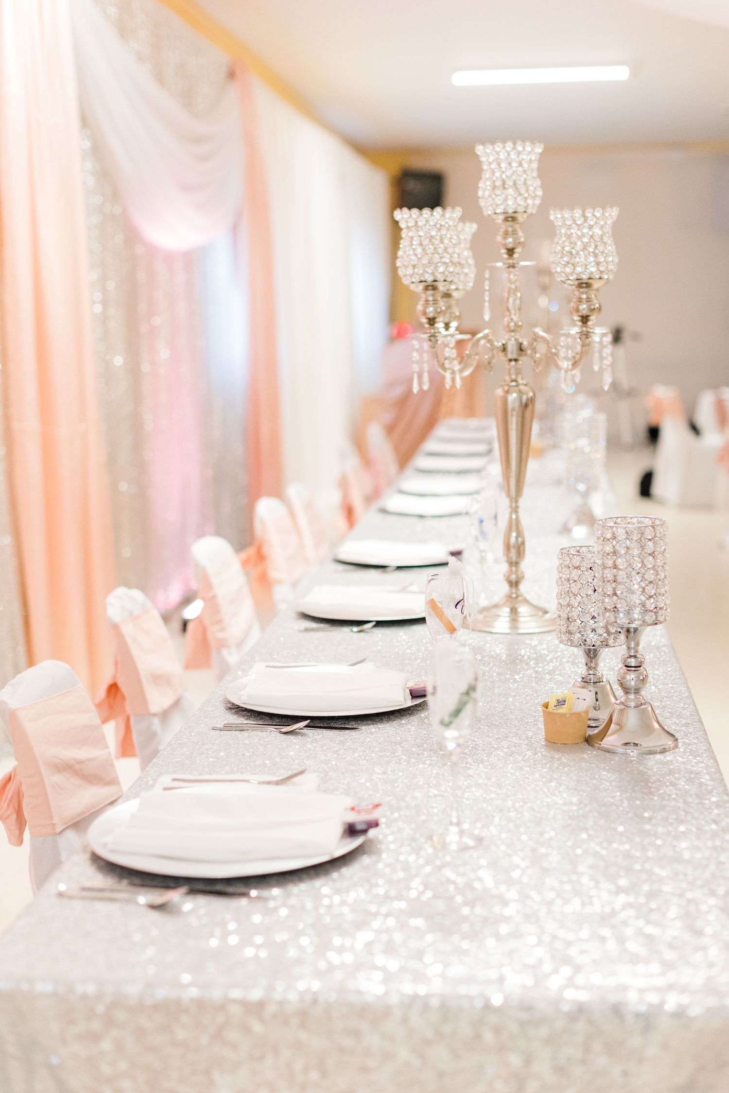 Luxurious table setting with crystal candelabras and peach chair sashes.