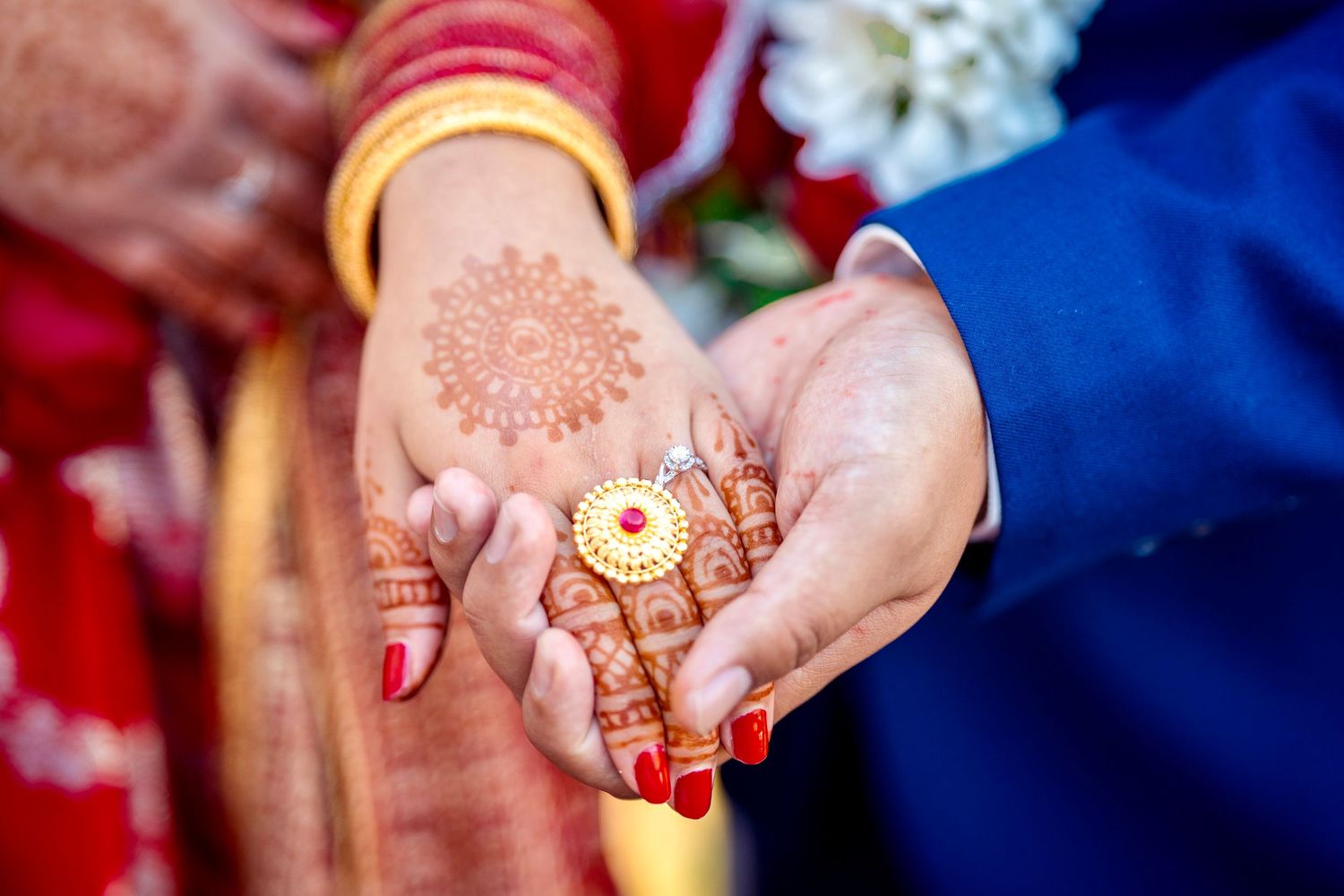 Close-up of hands holding traditional wedding jewelry with mehndi designs.