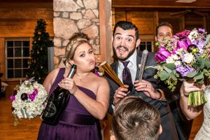 Fun celebration moment at a rustic wedding reception with purple florals and decorations.