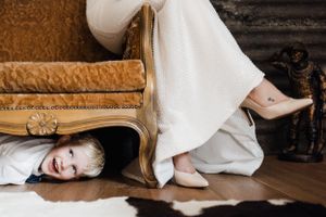 A playful moment under vintage furniture during a wedding photo session.