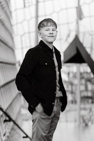 Black and white portrait of young person wearing dark jacket against geometric background.