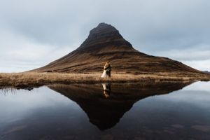 Scenic mountain reflection in still water with dramatic cloudy sky in Iceland.