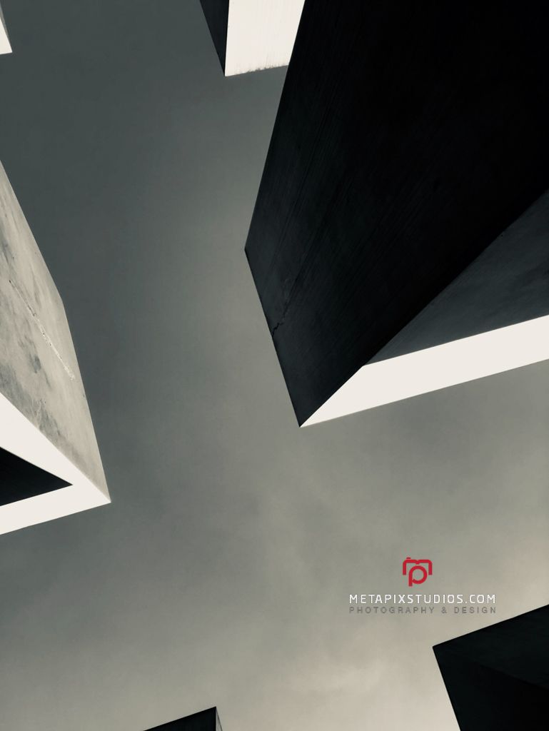 Dramatic low angle black and white photo of tall concrete monument slabs.