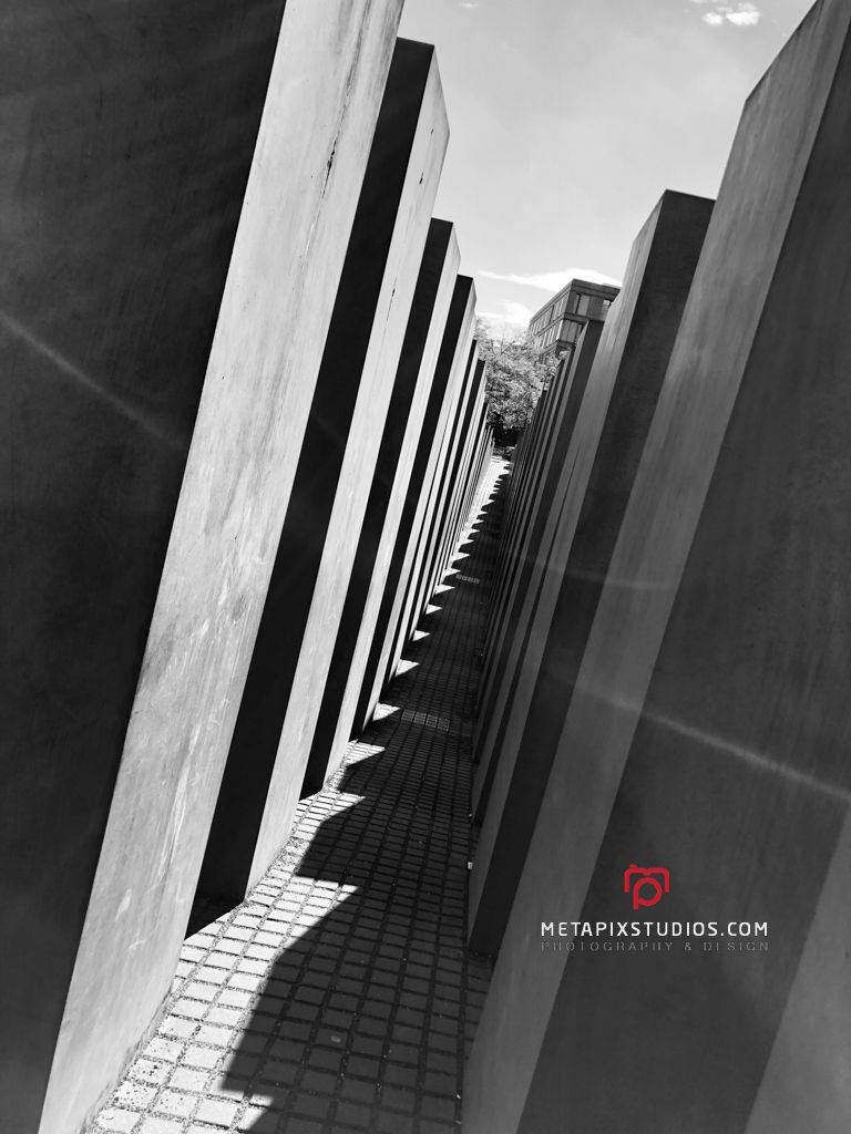 Black and white shot of towering concrete stelae with dramatic shadows at the Holocaust Memorial Berlin.