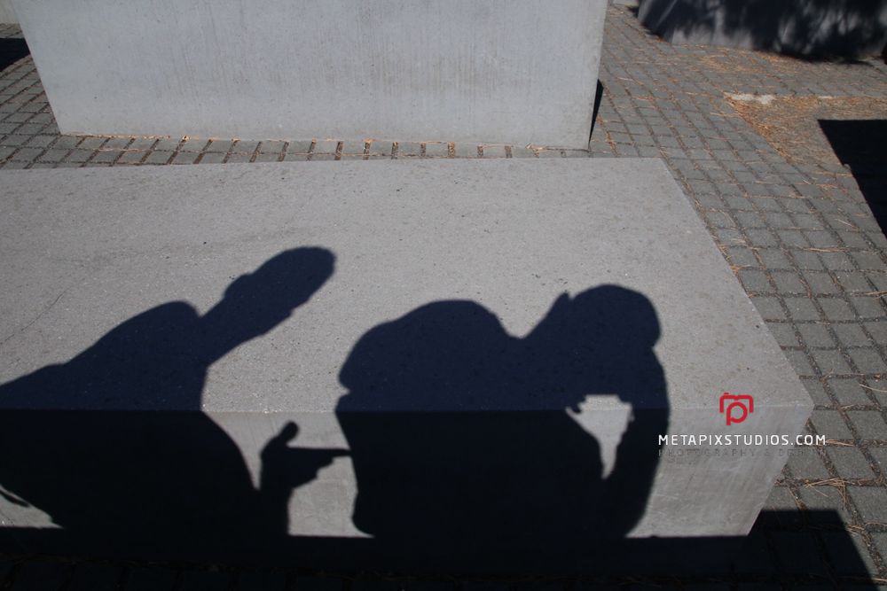 Shadow silhouettes of two people projected onto a concrete stele at the Holocaust Memorial Berlin.