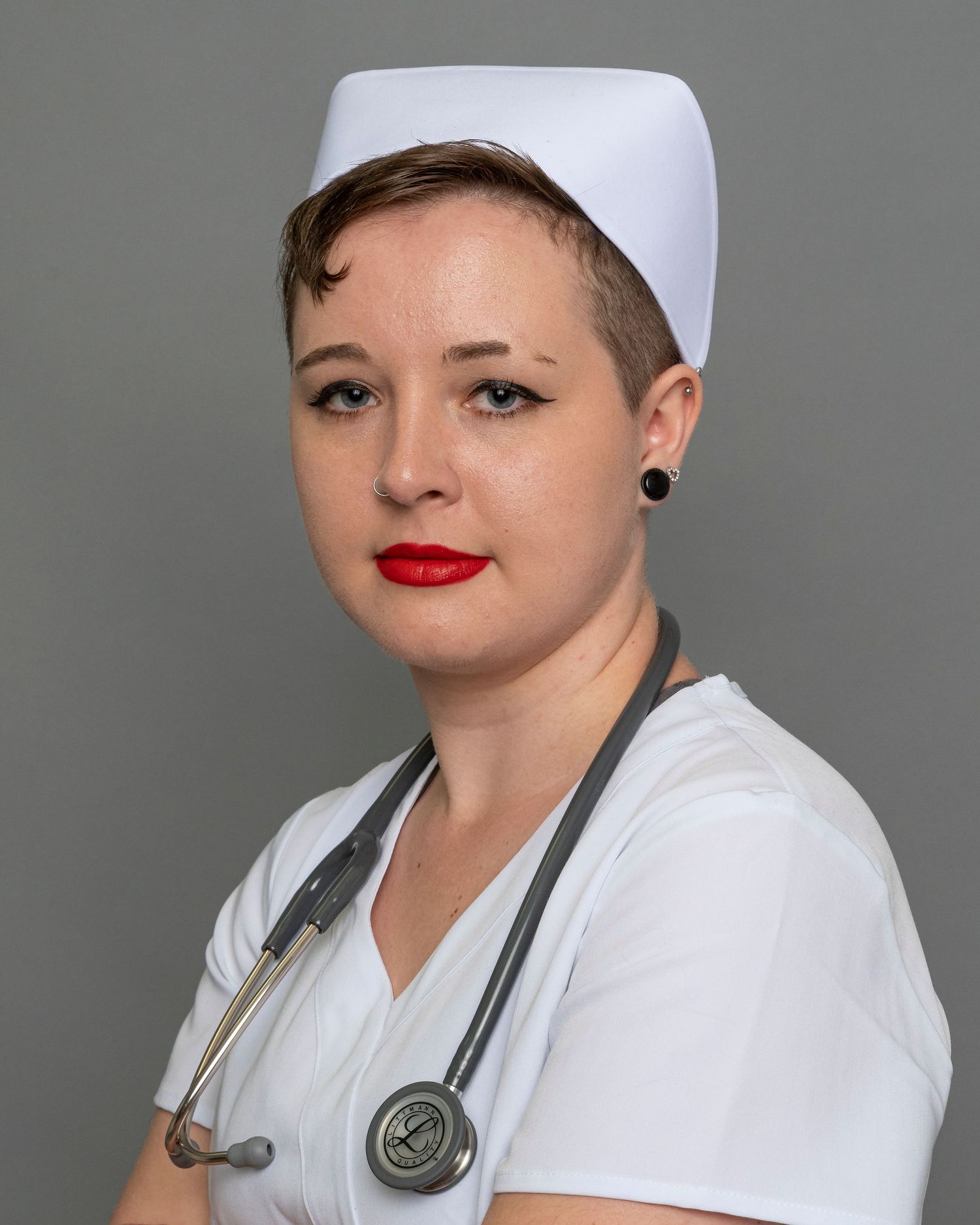 Healthcare worker wearing traditional white nurse cap and stethoscope in professional portrait.
