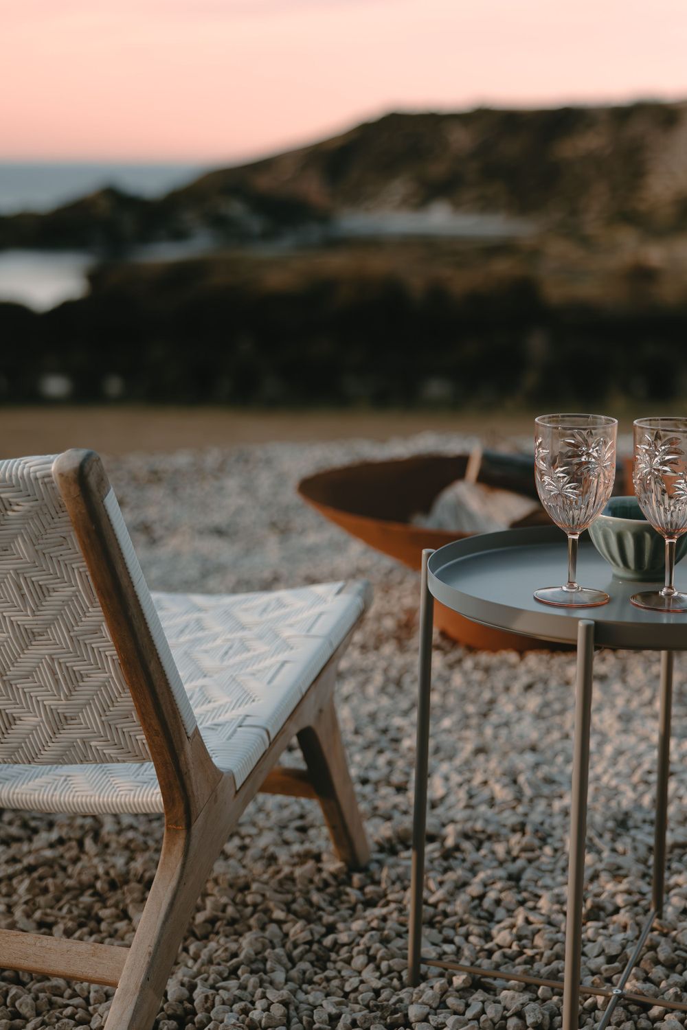 Elegant outdoor dining setup with crystal glasses on modern furniture at sunset.