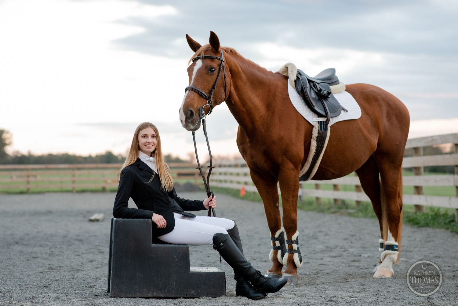 Equestrian portrait with saddled horse in riding arena during cloudy day.