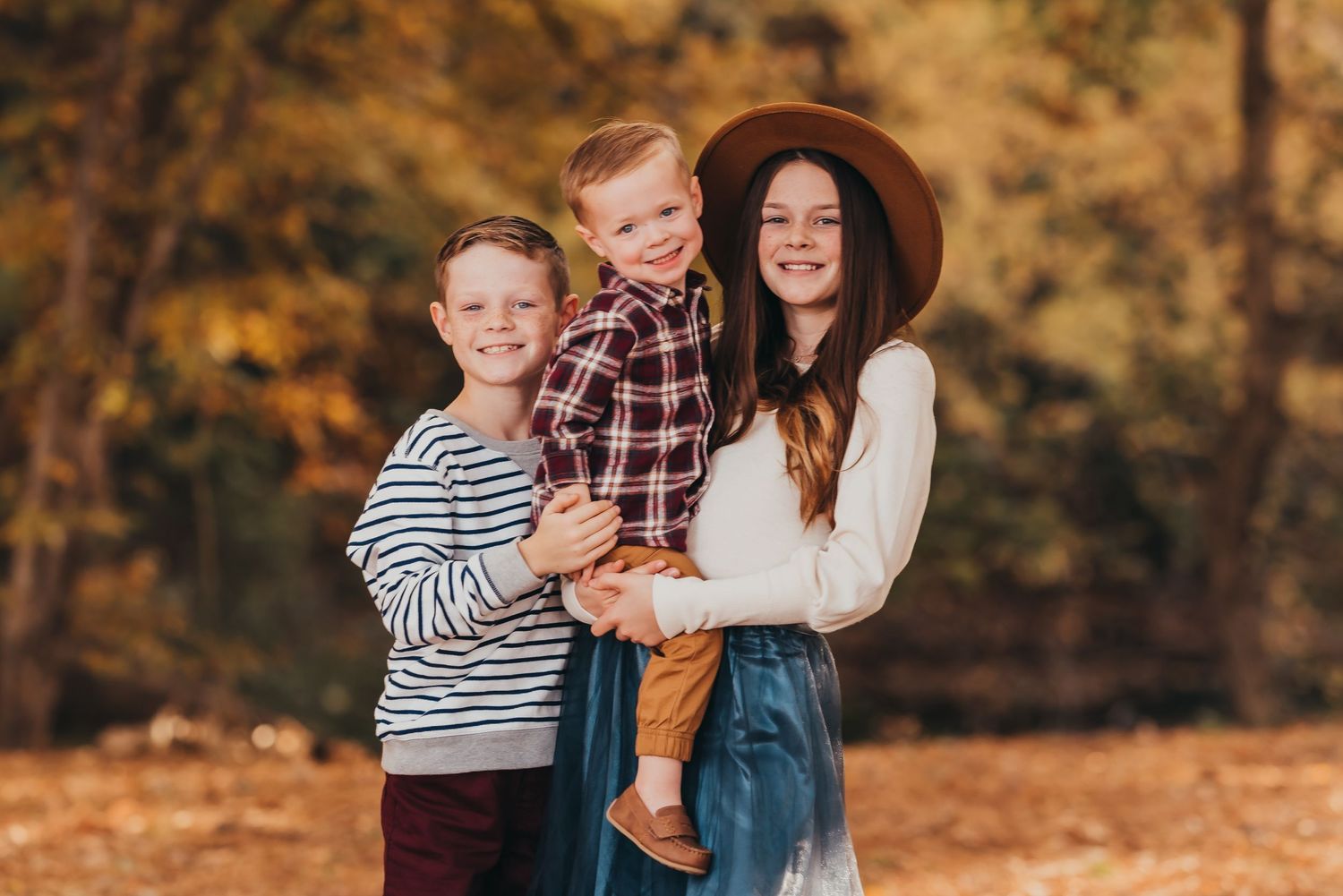 Fall family portrait captured outdoors with autumn foliage in the background.