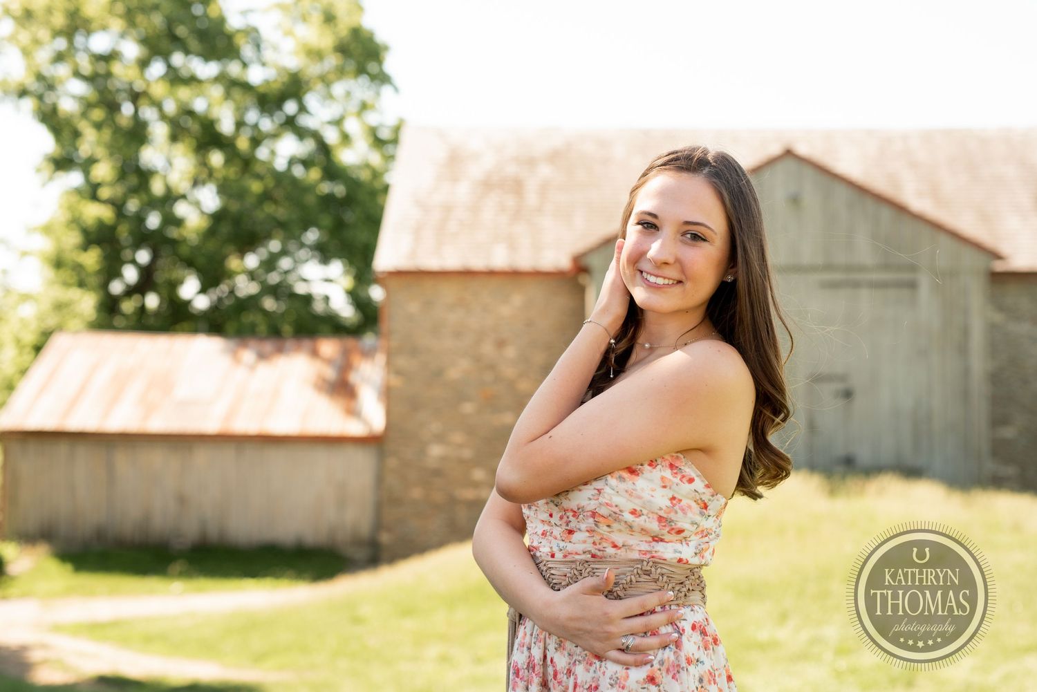 A summer portrait session in front of a rustic barn on a sunny afternoon.