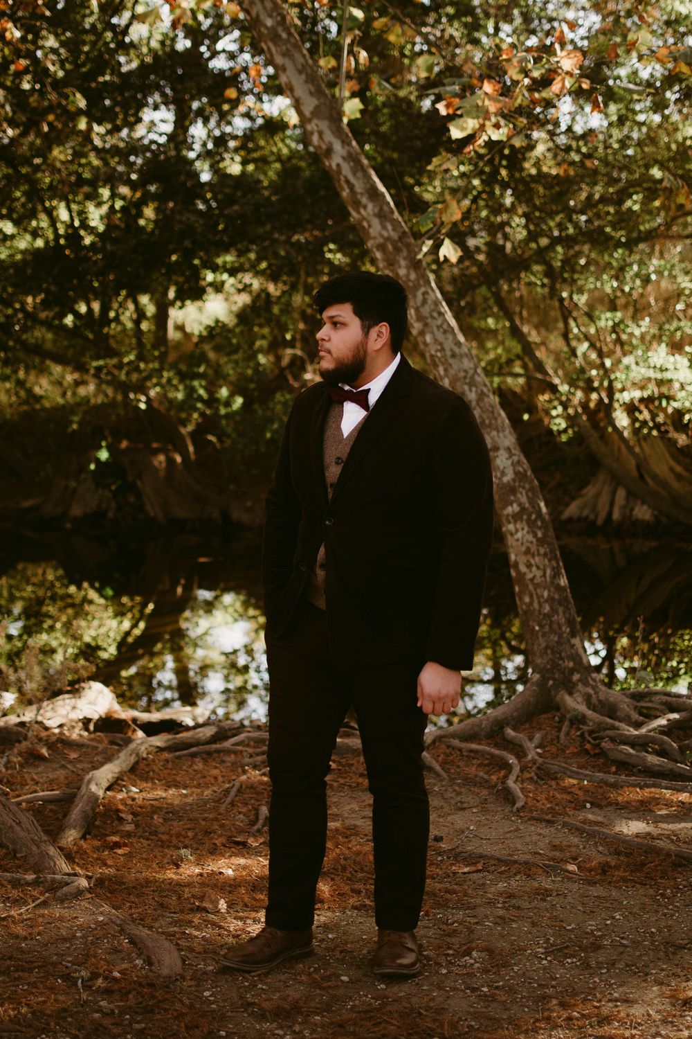 Elegant formal wear portrait captured in natural wooded setting with dramatic lighting.
