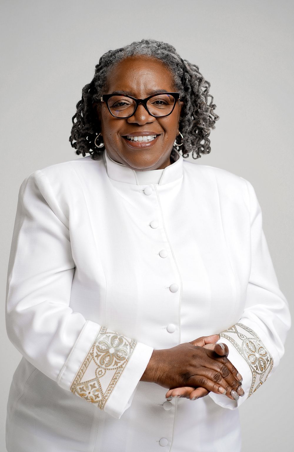 Professional headshots showing person in white jacket with embroidered details against light background.