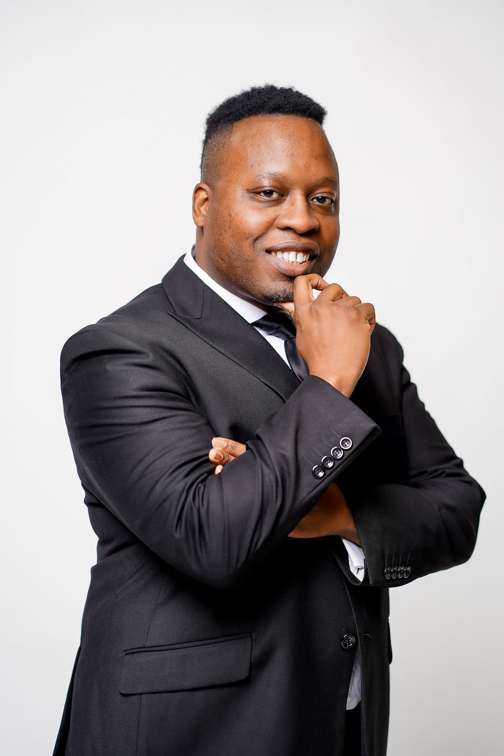 Professional headshots of person in dark suit posing confidently against white backdrop.