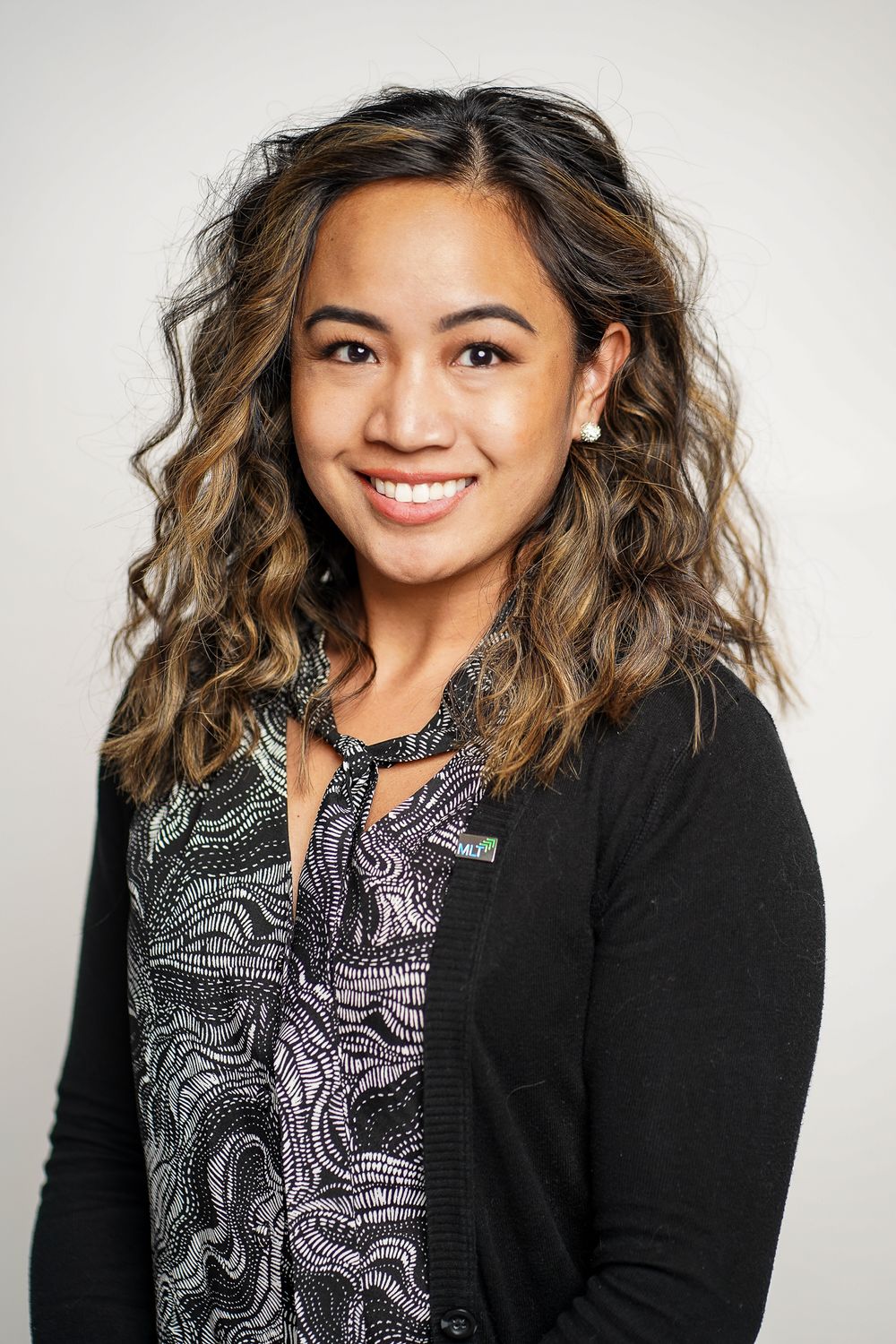 Studio portraits featuring stylish black cardigan and patterned top against white background.