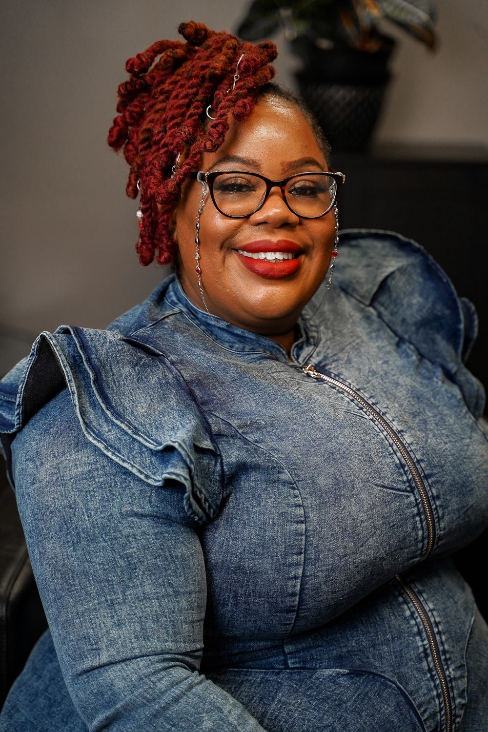 Casual portraits in denim jacket with red hair against dark studio background.