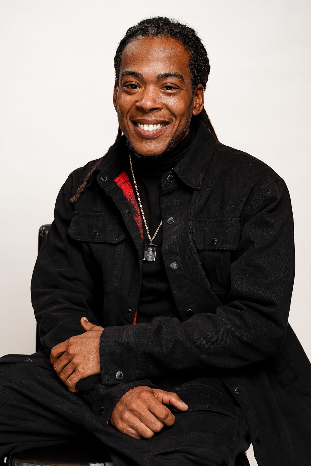 Studio portraits of someone wearing a black jacket with red accents against white background.