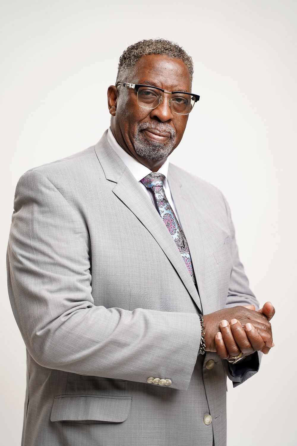 Portrait series of someone in a light grey suit and purple tie posing against white background.