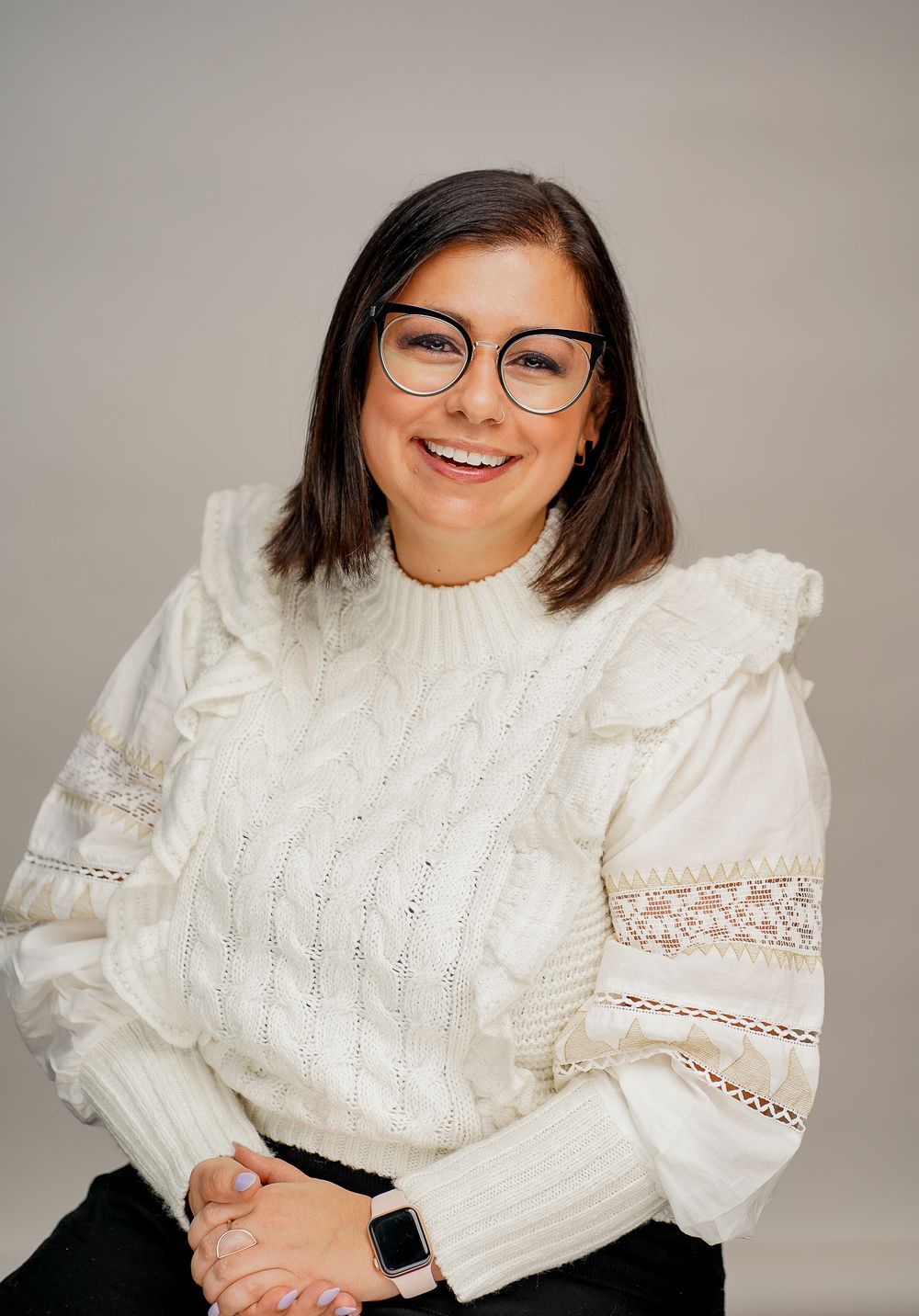 Studio portraits showing someone in a white cable knit sweater against neutral background.