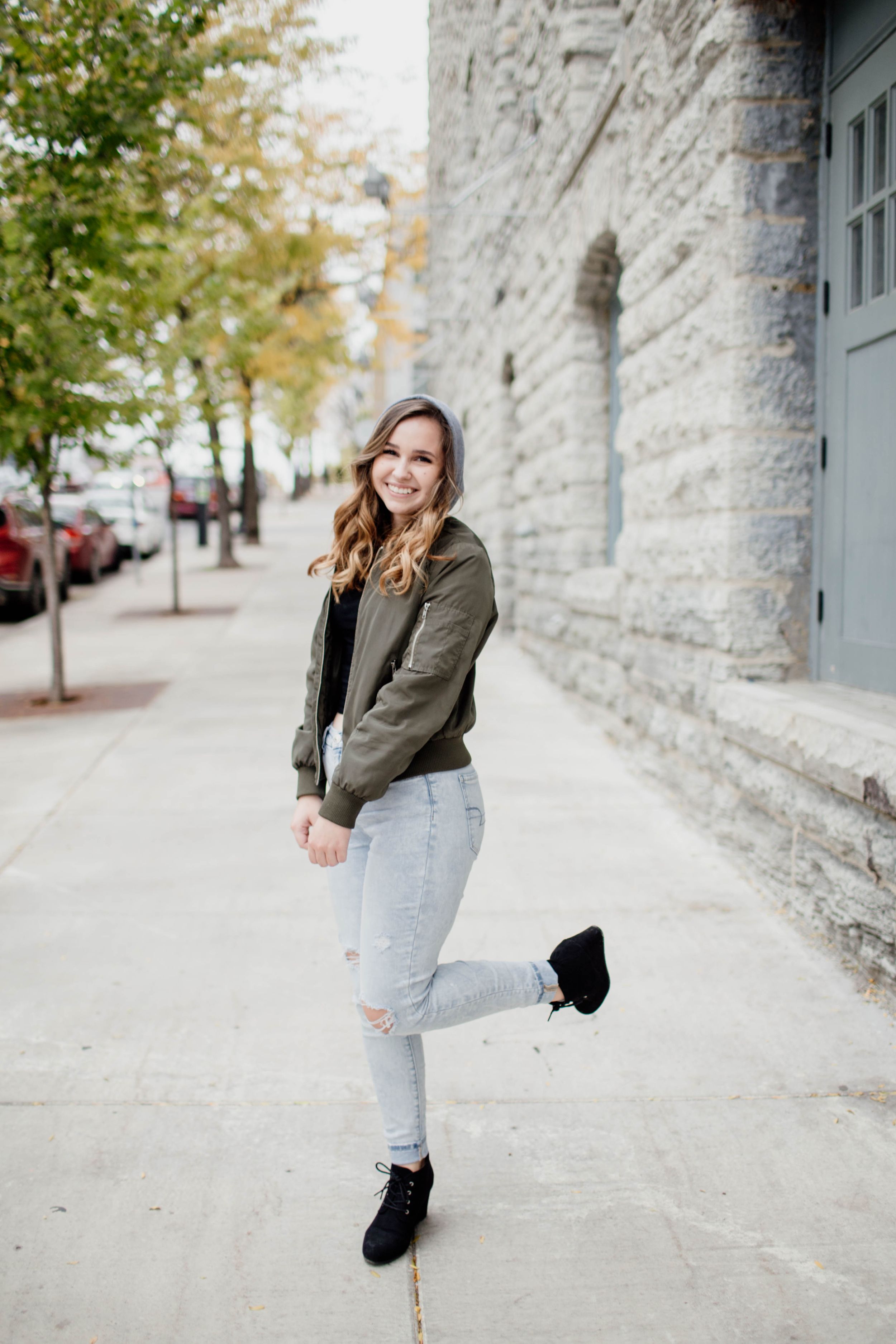 Urban street scene with stone wall backdrop and casual autumn fashion.