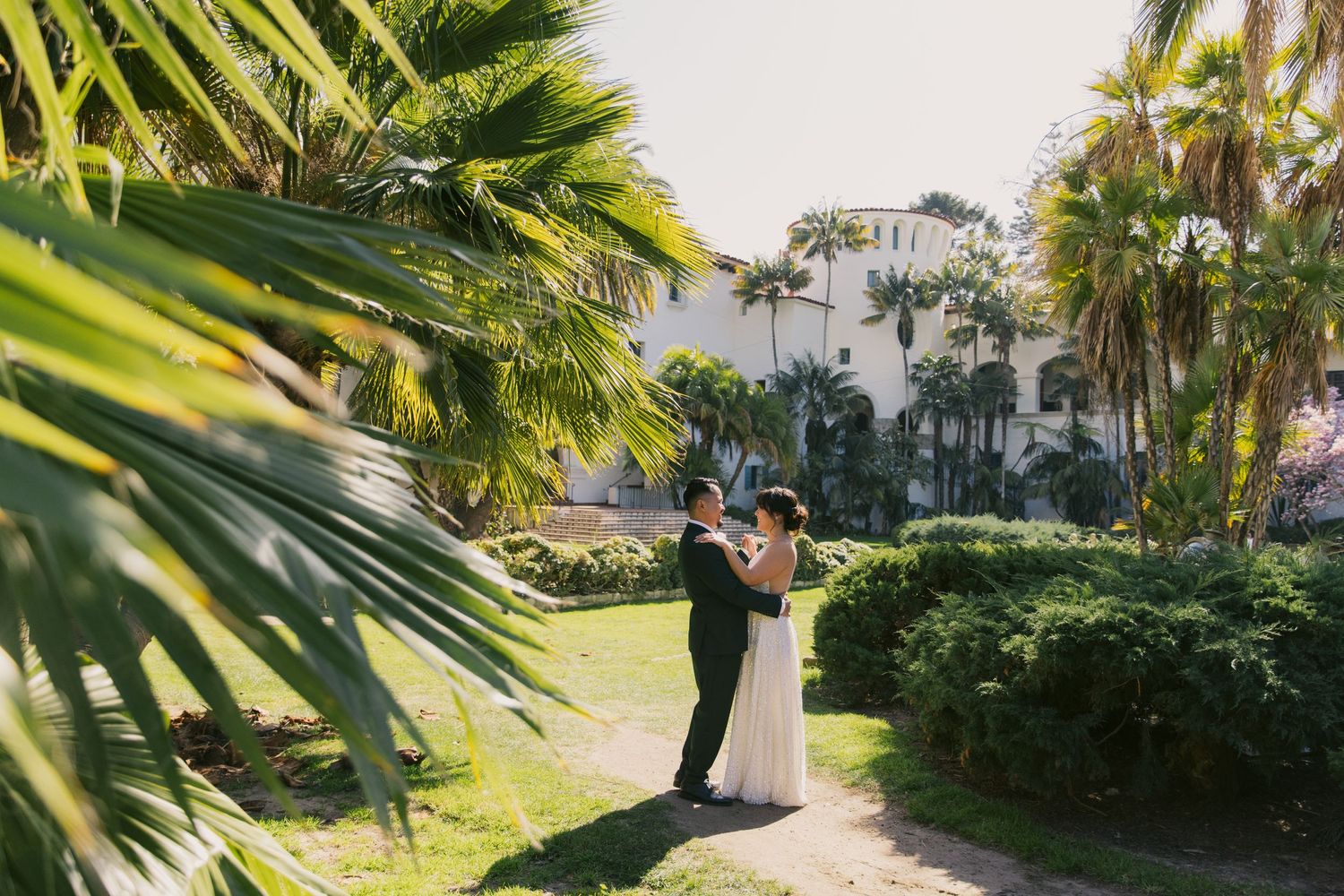 Elegant wedding portraits among tropical palm trees and lush greenery.