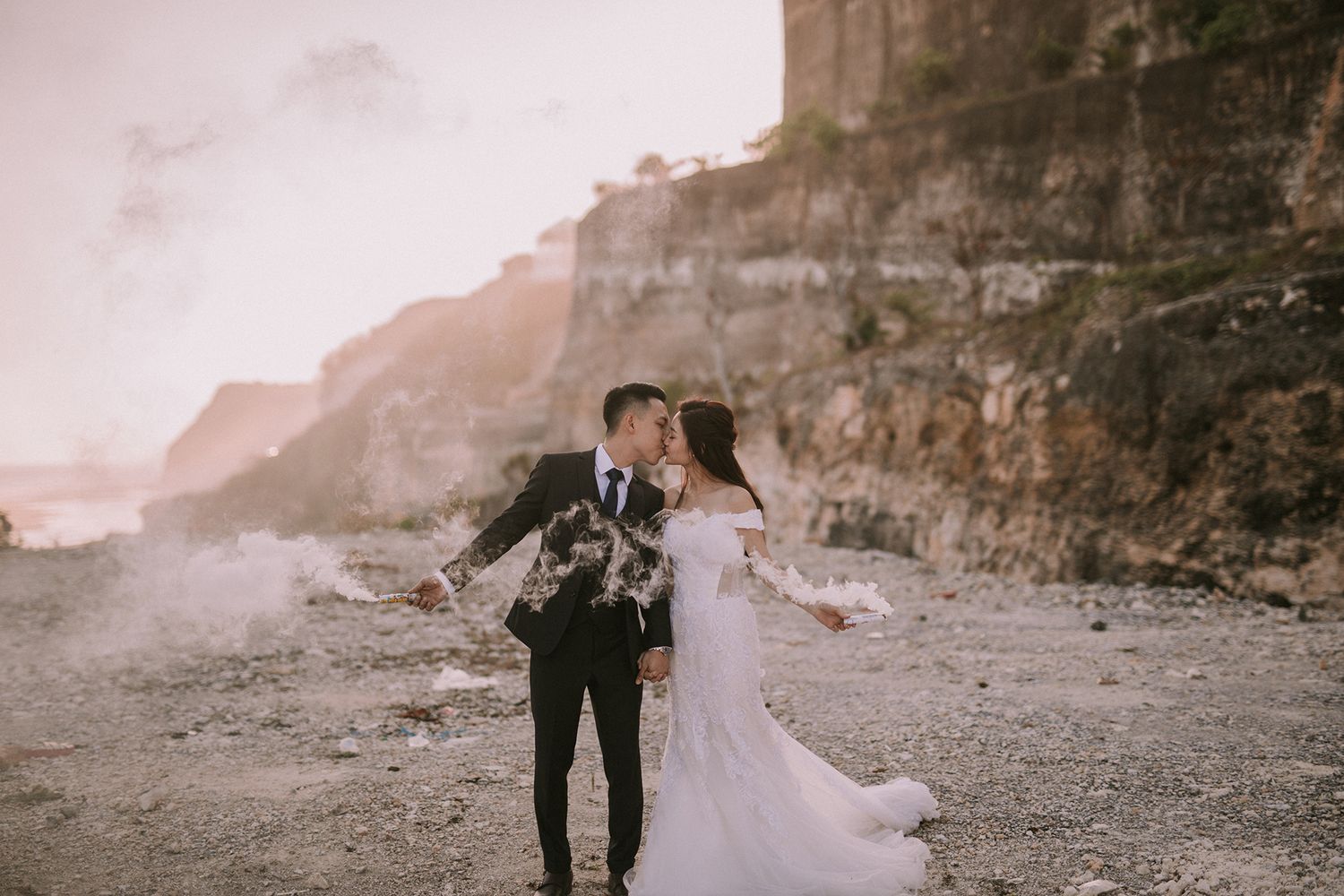 Romantic photoshoot at a rocky coastal cliff during golden hour.