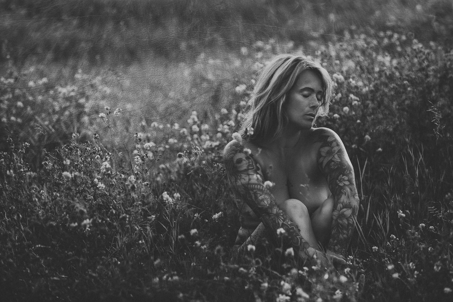 woman sitting in a field of wildflowers at sunset