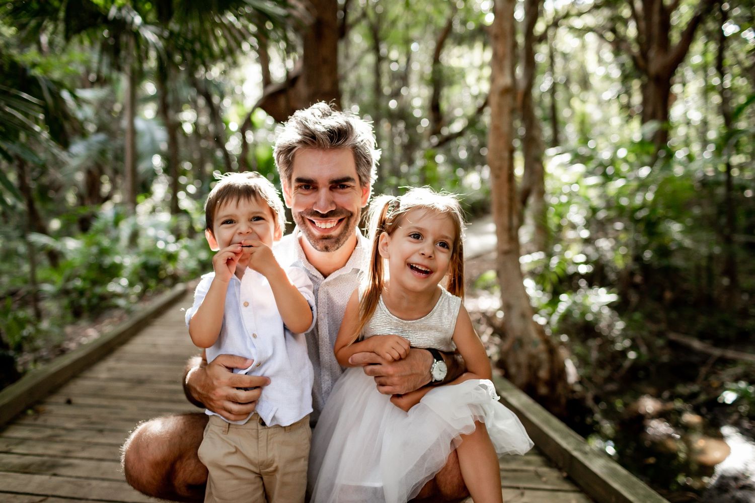Energetic family photo with expressions of joy on forest boardwalk.