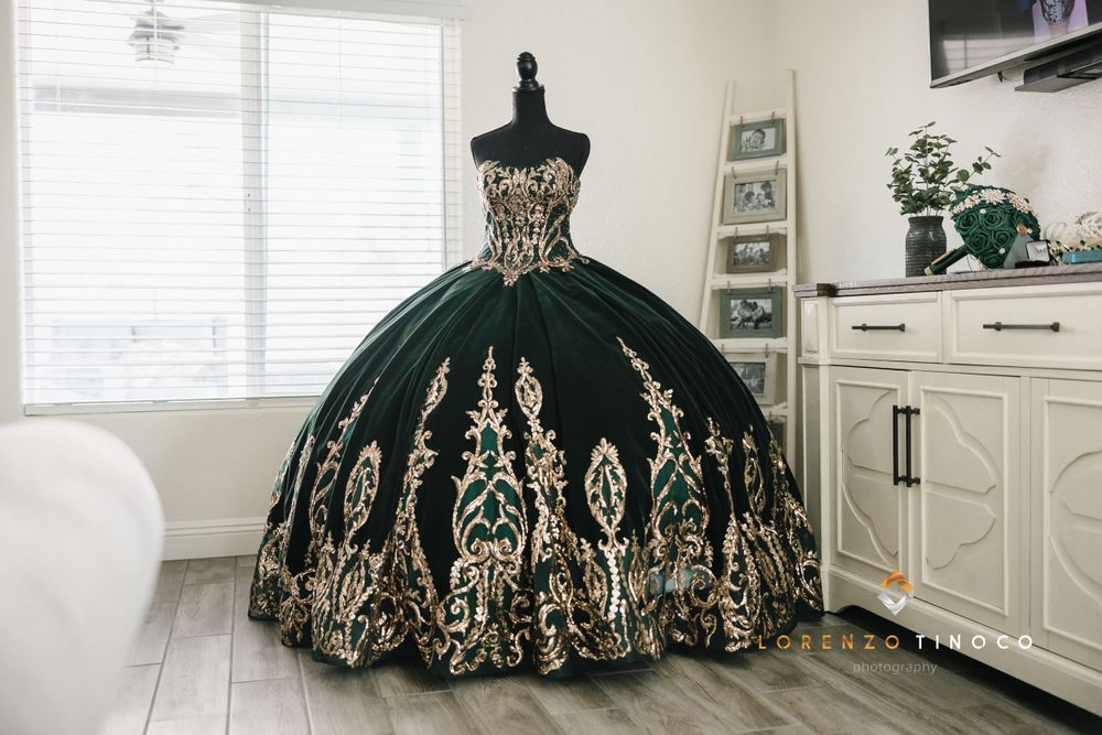 An elegant black ball gown with gold embroidery displayed on a mannequin in a bright room.