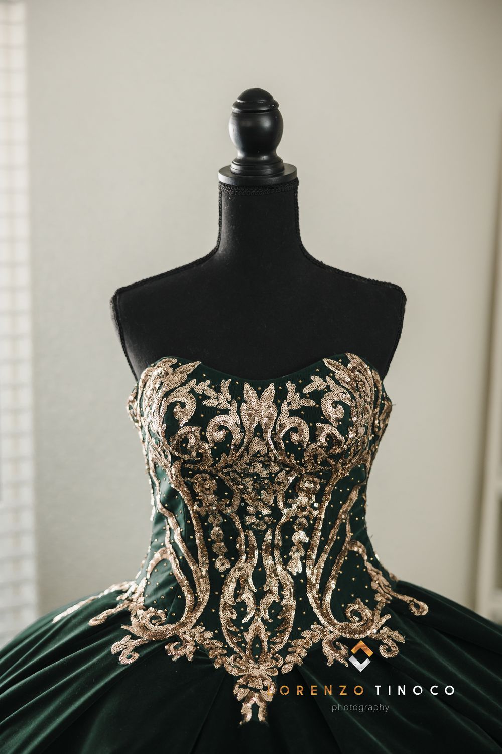 Close-up detail of intricate gold embroidery on a dark green strapless ballgown bodice.