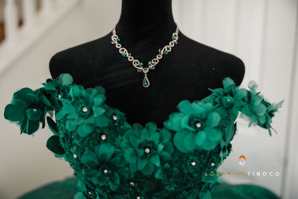 Emerald green dress bodice with floral details and crystal necklace on black mannequin.