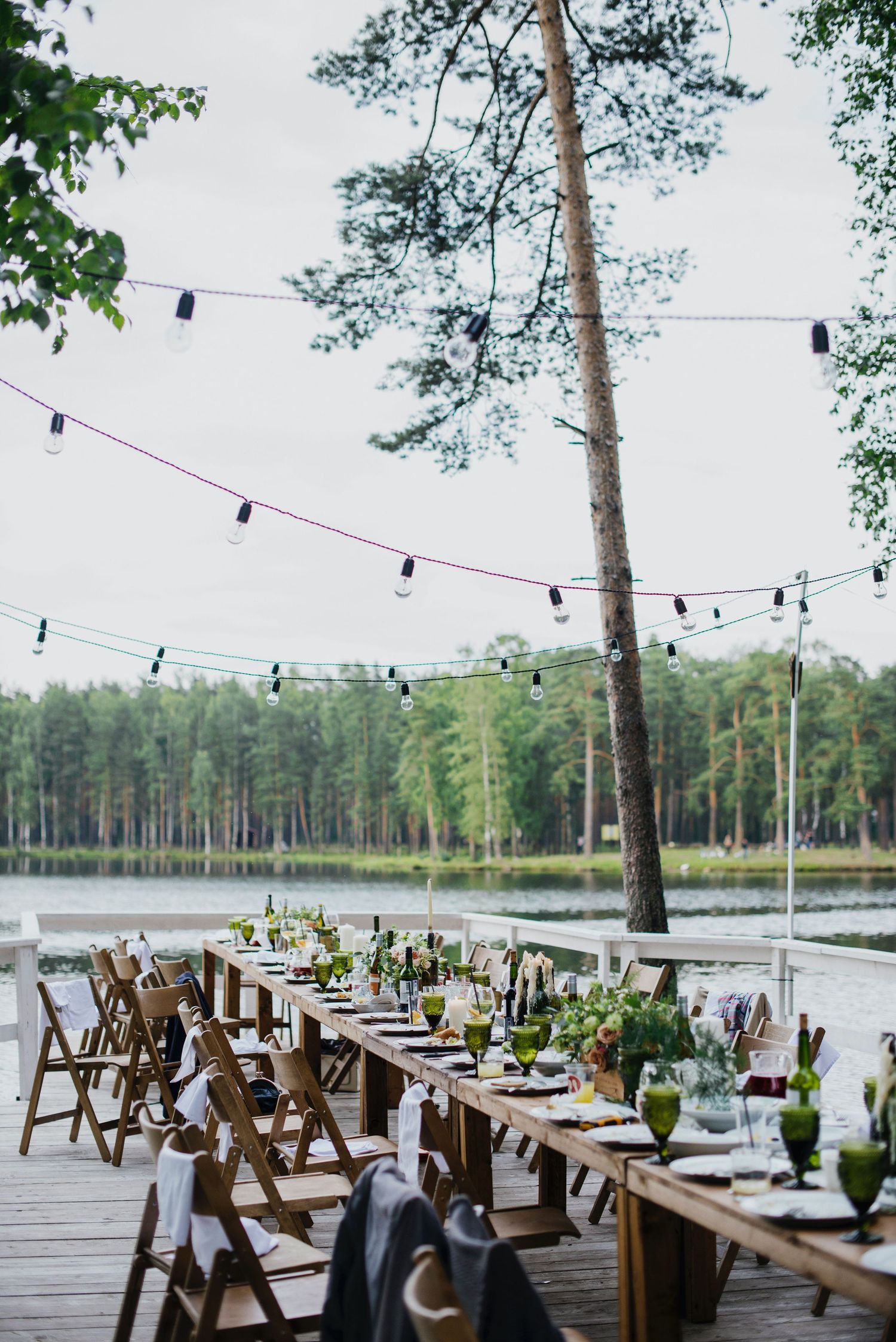 Ceremony table of guests with wine and meals in front of a lake
