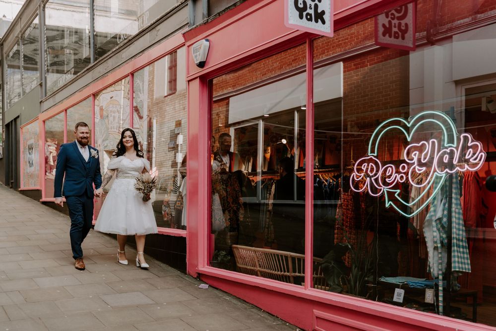Bride and groom walking outside a Lucy and Yak shop.