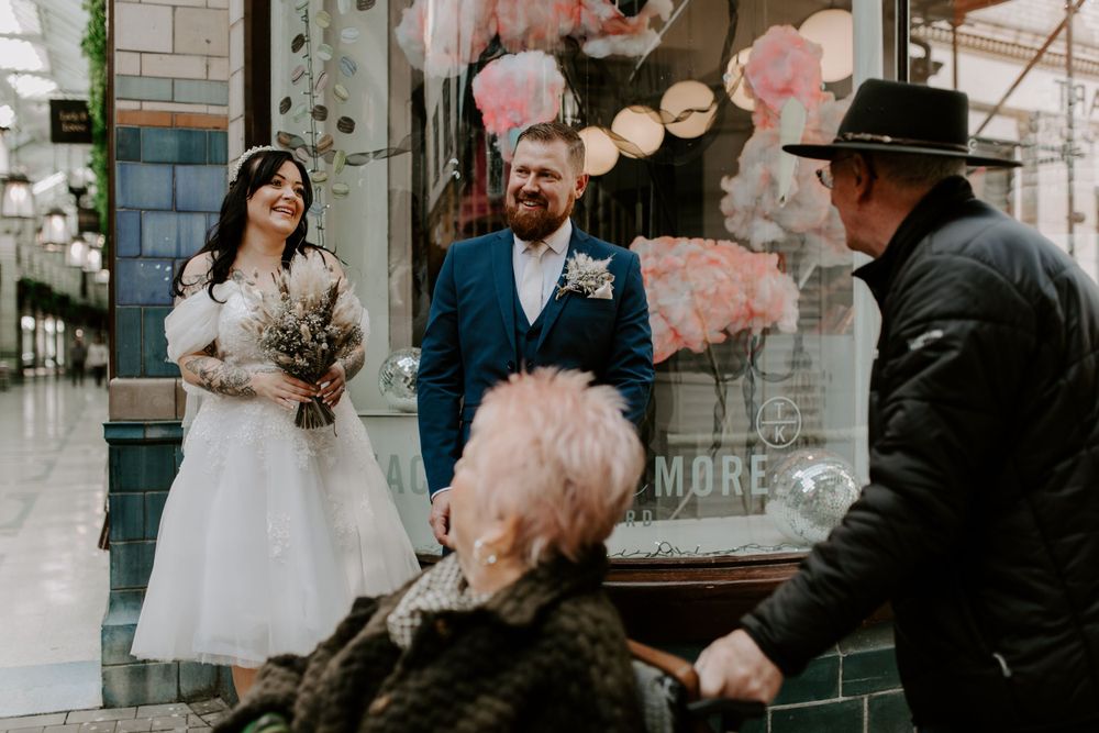 a couple are stopping to congratulate a bride and groom in the city centre.