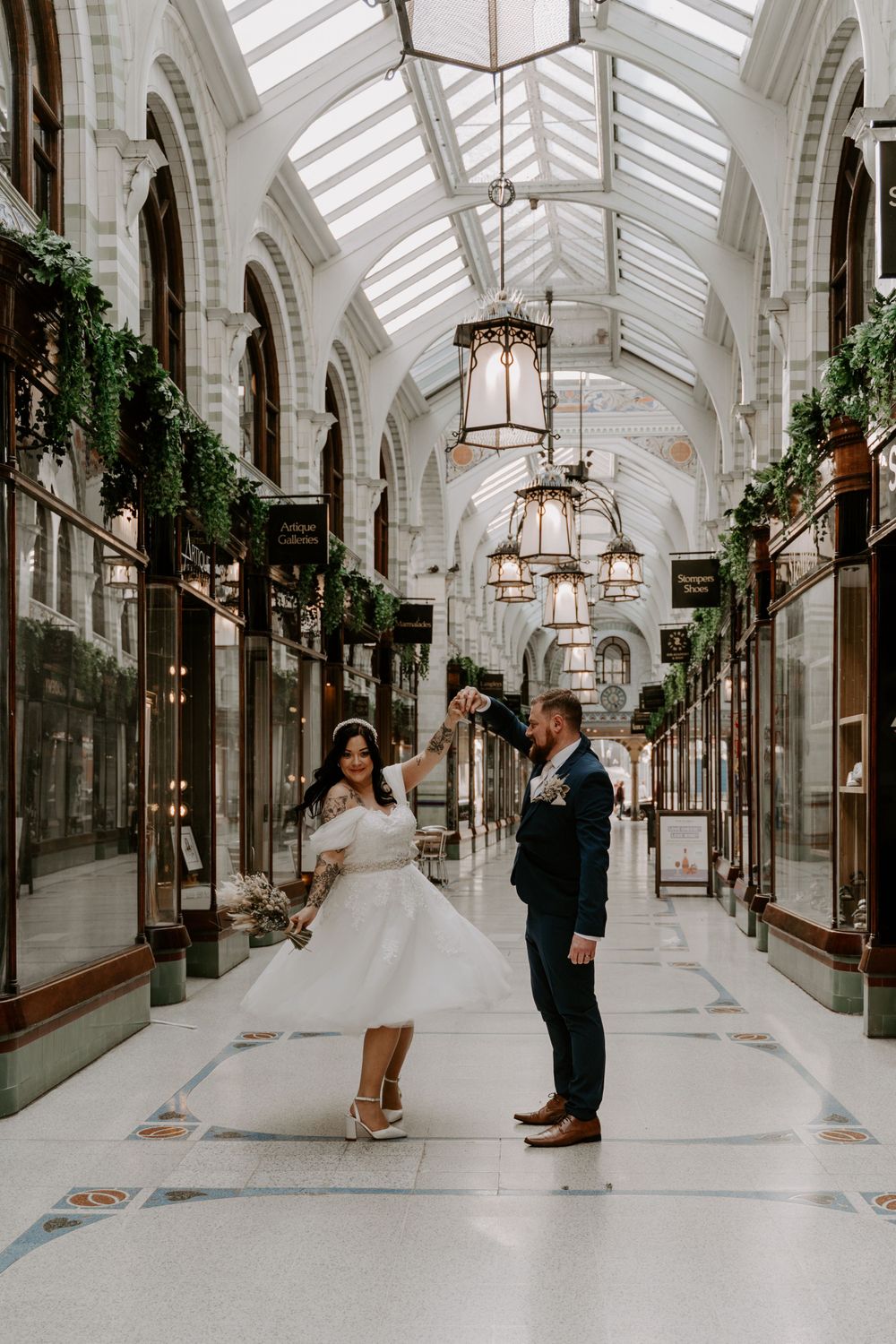 bride and groom dancing in a shopping mall. Bride is twirling round and laughing.